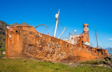 Ahşap rıhtımın yanında paslı yaşlı balina avcısı.