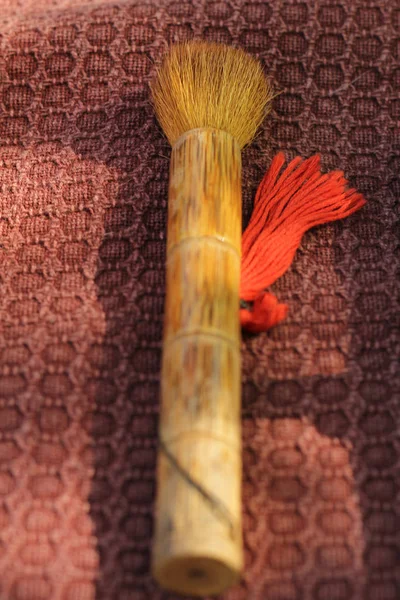 red brush with bamboo handle on burgundy fabric