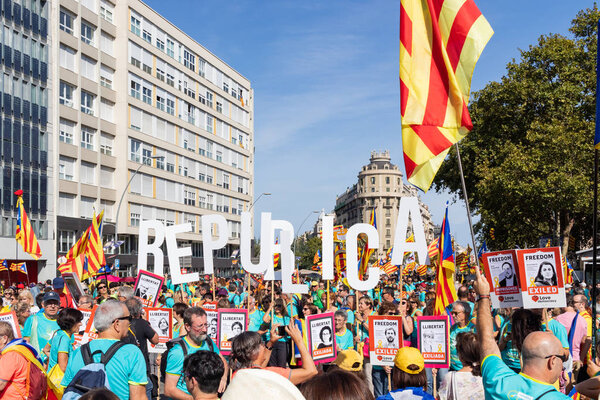 People holding "Republica" word and banners claiming the freedom for some exiliated and prisoner Catalan politicians. Independentist rally at La Diada, Catalonia's National Day.