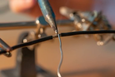 Lehim demiriyle lehimlenmiş iki siyah kablo.