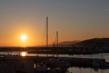 Birden fazla yelkenlisi olan bir limandan dramatik bir gün batımı.
