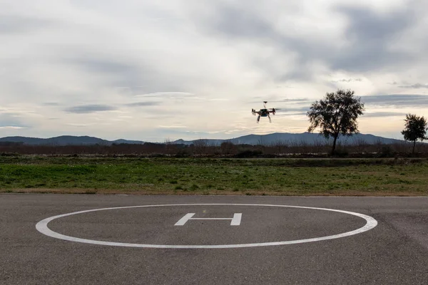 Drone stijgt op vanaf een kleine helikopter landingsplaats tegen bewolkte lucht. — Stockfoto