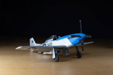 P-51 Mustange ölçeği siyah arka planlı tahta üzerinde uçak modeli.