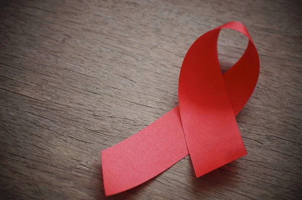 Красная лента на деревянном фоне, знак СПИДа с копировальным местом — стоковое фото