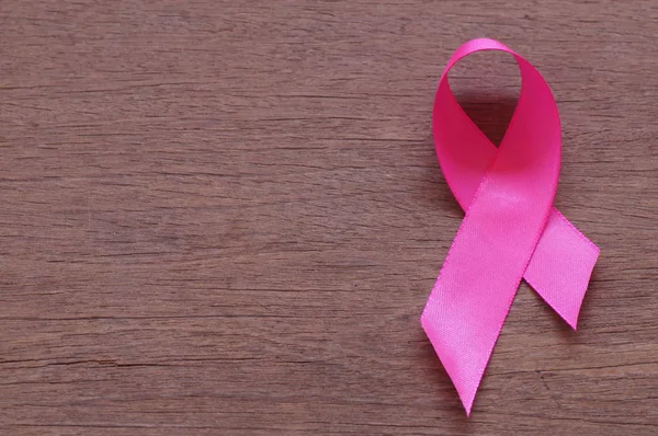 Рак молочной железы розовой ленты на фоне дерева с копировальным пространством — стоковое фото