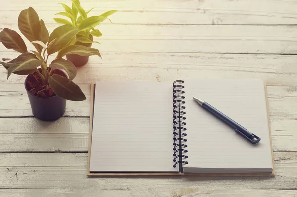 Açık kitap masada kağıt kalem ile kaplı.