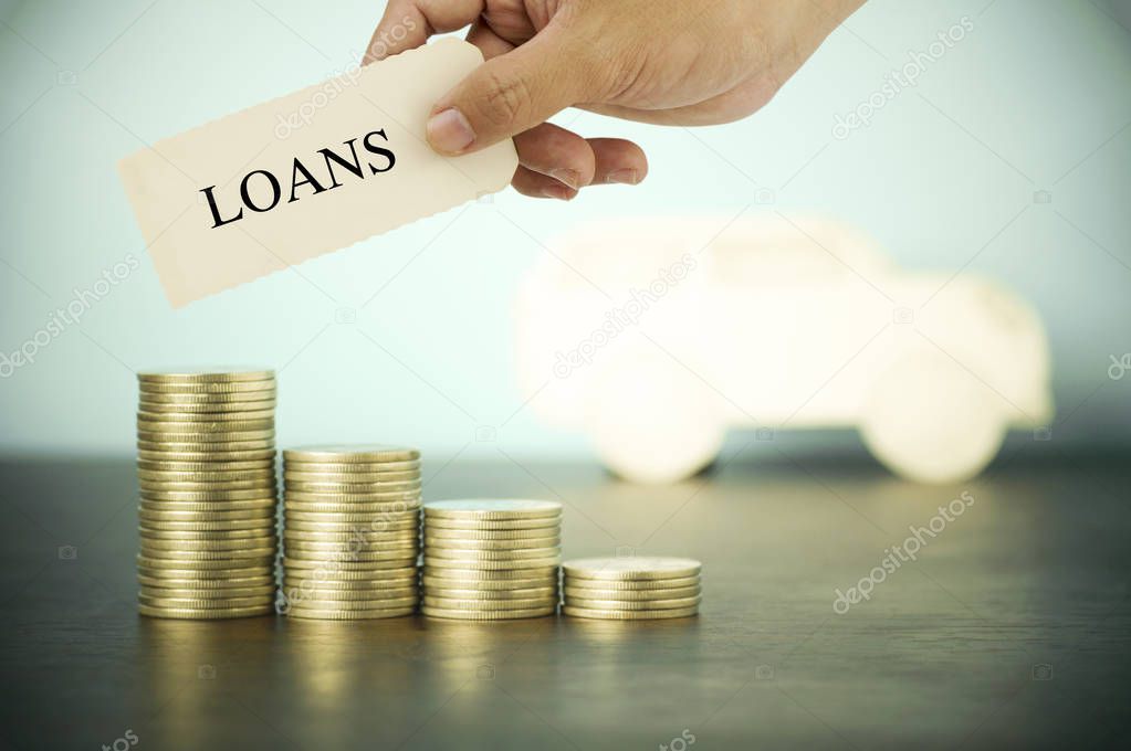 hand hokding and show loans sign on pile of money coins , concept in buying, selling and car finance