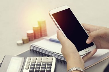 Paralar, defter ve hesapla yığını ile akıllı telefon kullanan kadın