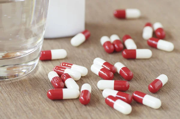 Capsule and glass of water on wood table — Stock Photo, Image