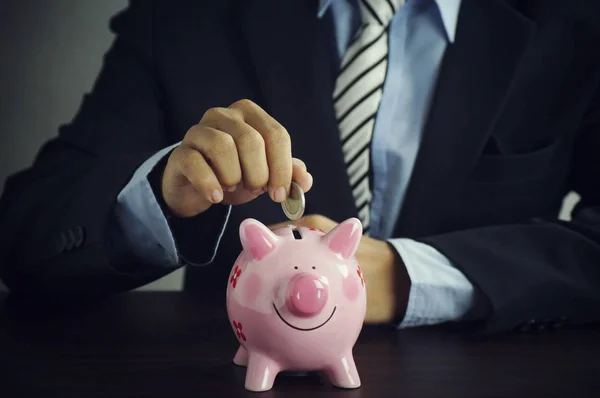 Busineeman put money on piggy bank on desk, concept in save and investment in business — Stock Photo, Image