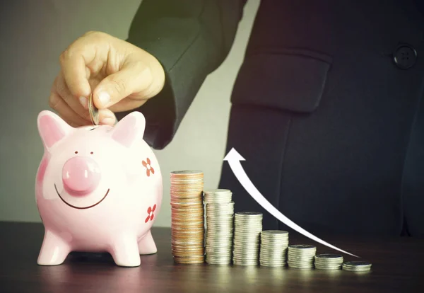 Hand of businesswoman put money on pink of piggy bank and  pile of coins on blue background, concept in growth, save and investment in business — Stock Photo, Image