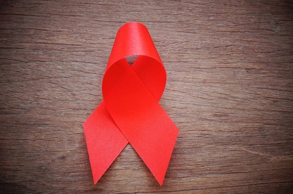 Красная лента на деревянном фоне, знак СПИДа с копировальным местом — стоковое фото