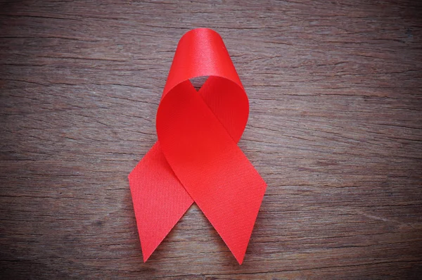 Красная лента на деревянном столе, знак СПИДа — стоковое фото