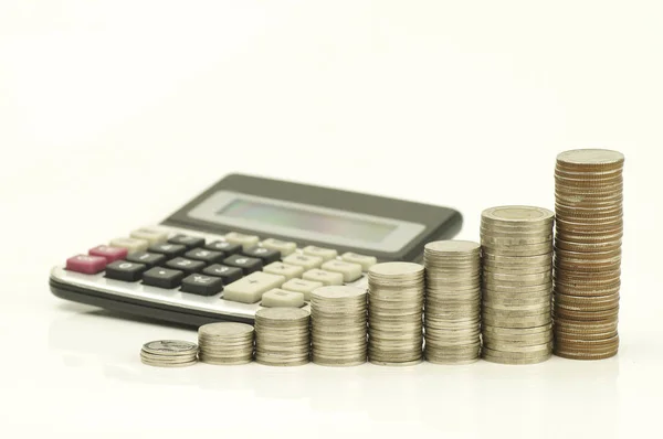 Куча монет и калькулятор изолированы на белом фоне — стоковое фото