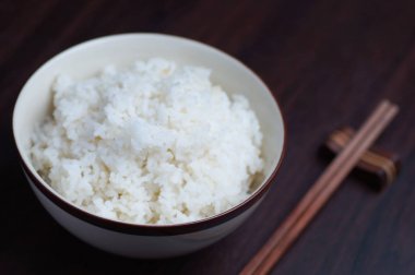 Ahşap arka plan üzerinde yemek çubukları ile Tayland pirinç