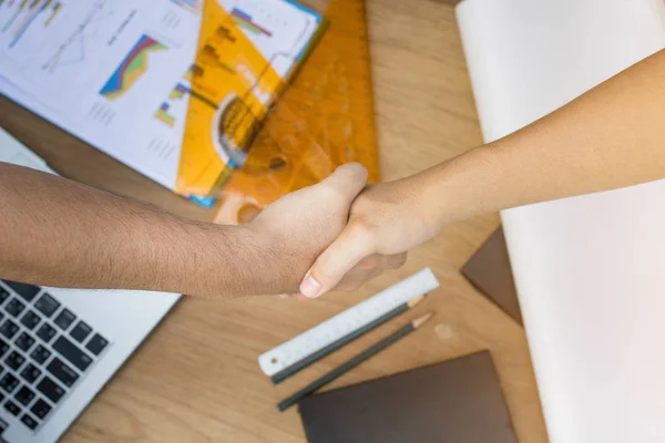 Bovenaanzicht van twee ingenieur schudden hand op houten tafel met gereedschap een — Stockfoto