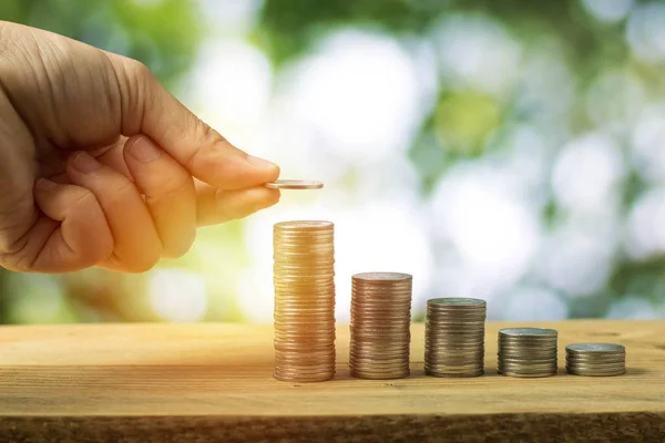 hand stacked money coins and green bokeh background, concept as