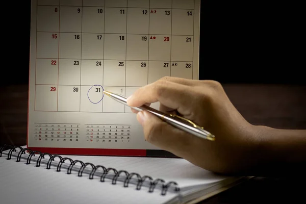 カレンダー上の日付をメモまたは作ると計画手持株ペンとポイントのカレンダーに書いてペンで手します — ストック写真