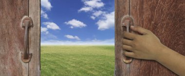 eski ahşap kapı veya pencere grung yeşil doğa ve gökyüzü arka plan görmek için kolları ile açılış el