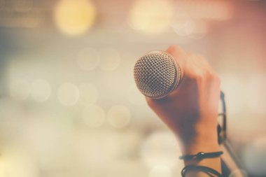 Stüdyo Oda ve toplantı salonu müzik enstrümanı olarak mikrofon ve bokeh arka plan, kavram tutan el