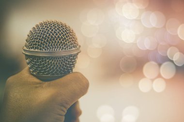 Stüdyo Oda ve toplantı salonu müzik enstrümanı olarak mikrofon ve bokeh arka plan, kavram tutan el