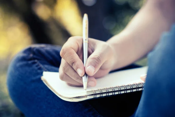 Primer plano de las mujeres jóvenes que escriben en el cuaderno en el parque, concepto en edu —  Fotos de Stock