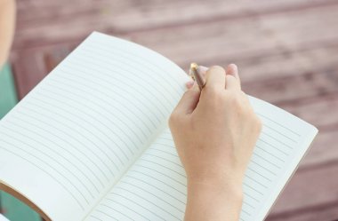 genç kadın yazma not defterinde park, edu kavramında kapatın