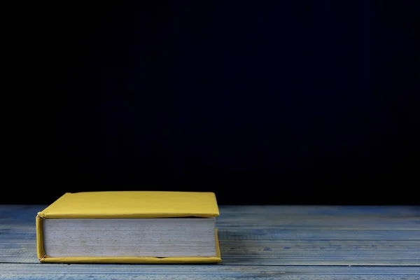 book on wood table and black  background, concept as opening paper will see knowledge of the world, learning by yourself and improve your life