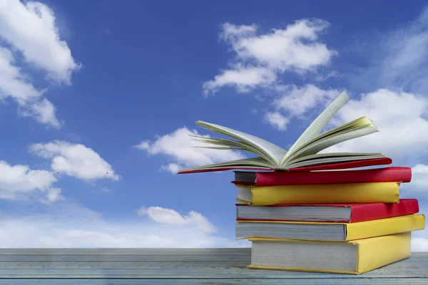 book on wood table and blue sky background, concept as opening paper will see knowledge of the world, learning by yourself and improve your life