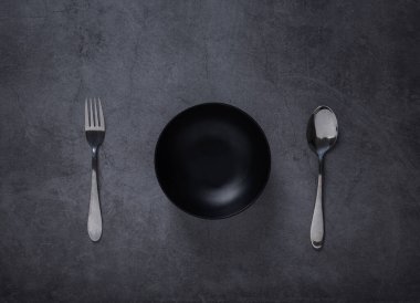 Kaşık ve boş kase üst görünümü koyu çimento arka planda