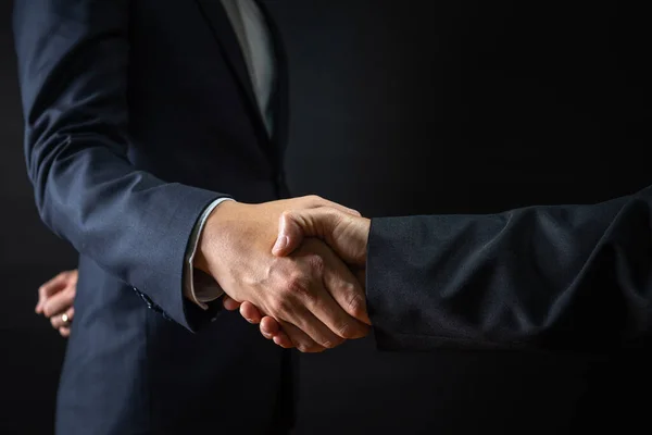 Business agreement and successful negotiation concept, businessman in suit shake hand with customer, client after formal communication and contract deal success on black background