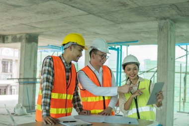 İnşaat alanındaki ahşap masada dizüstü bilgisayarı olan bir mimarla planlama.