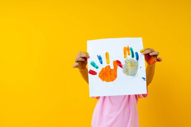 Sarı arka planda kağıt tutan genç bir çocuk. 