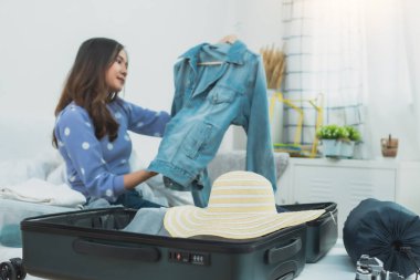 Tatil konsepti için hazırlık ve seyahat planı, Taylandlı ve Asyalı mutlu kadın valizlere bavul doldurup yatağa gitmek için hazırlanıyor.