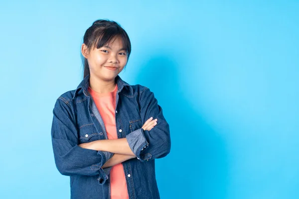 portrait of Asia girl, Thai teen smiled and looking camera on blue background in studio