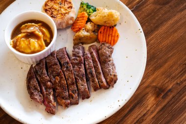 Tahta bir masada patates püresi ve sebzeli biftek.