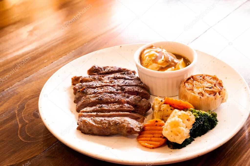 Beef steak with mashed potatoes and vegetables on a wooden table