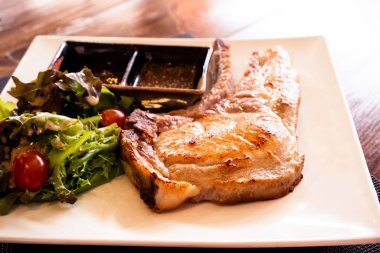 Tahta bir masada sebzeli domuz pirzolası.