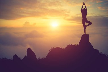 Pratik Yoga muontain üzerinde günbatımında siluet genç kadın