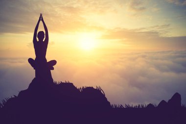 Pratik Yoga muontain üzerinde günbatımında siluet genç kadın