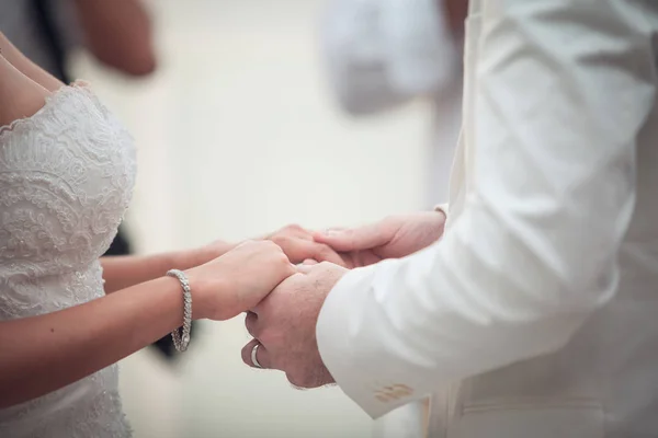 Pareja de boda cogida de la mano en el fondo de la puesta del sol. — Foto de Stock