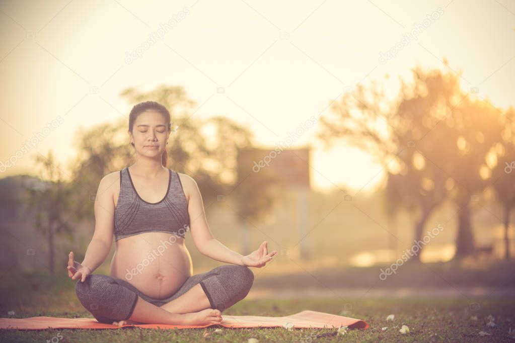 healthy pregnant woman doing yoga in nature outdoors.Vintage col