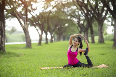 Genç kadın parkta yoga yapıyor.