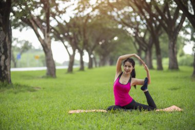 Genç kadın parkta yoga yapıyor.