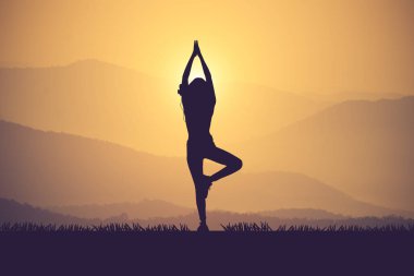 Pratik Yoga muontain üzerinde günbatımında siluet genç kadın