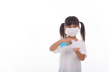 Beyaz arka planda alkol jeli kullanan küçük bir kız.