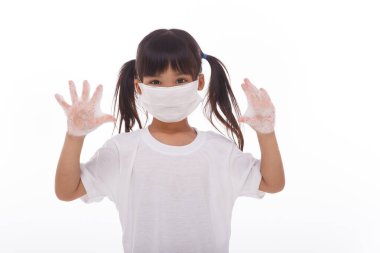 Çocuk ellerini yıkıyor ve beyaz arka planda sabunlu avuçlar gösteriyor.