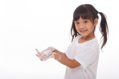 Çocuk ellerini yıkıyor ve beyaz arka planda sabunlu avuçlar gösteriyor.