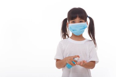 Beyaz arka planda alkol jeli kullanan küçük bir kız.