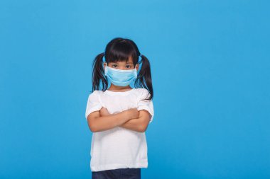 Koronavirüs salgınını korumak için solunum maskesi takan Asyalı küçük kız.